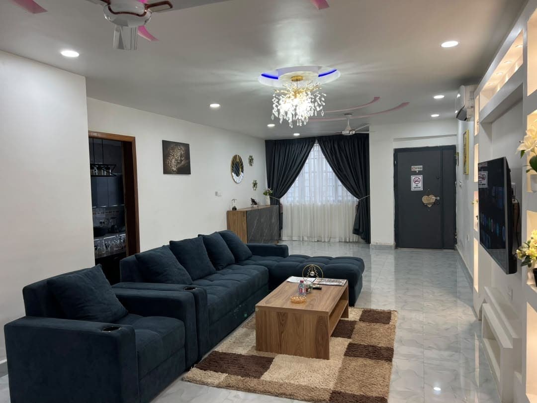 Unit 2 living room: a dark sectional sofa, a crystal chandelier and grey curtains